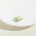 Adjustable golden evil eye ring with turquoise enamel finish on a white jewelry plate - Green
