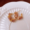 Detail van 18k vergulde oorbellen met aardbeienkristal en parels op een wit dienblad - Goud