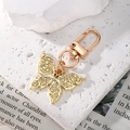 Macro shot of gold butterfly keychain with hollow patterns on textured white stone - Gold Butterfly