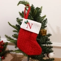 Red knit Christmas stocking with white cuff and embroidered letter N on a tree - Letter N