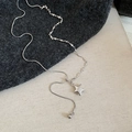 Detalle del collar con colgante de estrella plateada sobre tela de punto gris oscuro - Plata Asimétrica