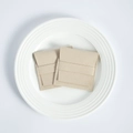 Detail of two beige microfiber jewelry pouches with flap closure on a white plate - Beige