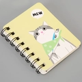 Close-up of yellow A7 notebook with a cartoon cat holding a fish and black spiral binding - Cat-Yellow