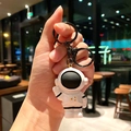 Portachiavi astronauta in resina bianca tenuto in mano in un accogliente bar di notte - Pezzo Singolo / Nero