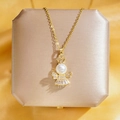 Collier ange doré avec œil de chat et zircons sur une boîte cadeau couleur champagne - Ange À Couronne De Perles Dorées