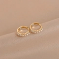 Macro shot of minimalist gold hoop earrings with small white pearls on champagne silk - Gold Pearl Earrings
