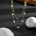 Elegant double-layered gold chain necklace with white pearls on a dark background - Gold