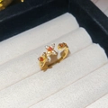 Macro detail of 18k gold plated open ring with orange zircon and floral star design - Gold-Red