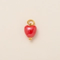 Detailed close-up of a small red heart charm with gold plating on beige texture - Red Enamel Heart