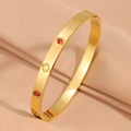 Elegant gold titanium bangle with clover pattern and ruby red crystals on beige fabric - Pink Zirconia / Gold