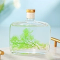 Flat rectangle glass bottle with gold cap, green clovers and white shells inside - Gardenia