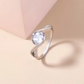 Detailed close-up of a silver ring with a round clear gemstone on a soft peach background - Adjustable Open / Clear Round Gemstone/Criss Cross Design