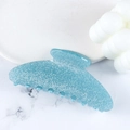 Sparkly blue glitter acrylic shark hair claw clip shown on white marble surface - Stone Green