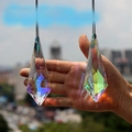 Two large K9 crystal prisms with iridescent rainbow shine held for size comparison - Long Horn 120mm