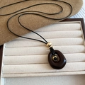 Detail of vintage resin tiger eye oval pendant necklace on beige fabric display - Round Style / Dark Coffee