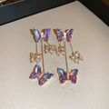 Detalle de pendientes de mariposa iridiscentes con cristales brillantes y borlas doradas - Azul-Púrpura (Pin de Plata)
