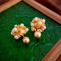 Detalle de pendientes de flores doradas vintage con perlas sobre vidrio decorativo - Pendientes de Botón de Flor de Perla Dorada (Pin de Plata)