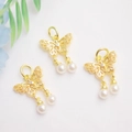 Detailed macro view of 14K gold-plated bow pendants with small rhinestones and pearls - 18K Gold Plated/White Zircon