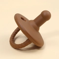 Brown silicone baby teether pacifier close-up view on a clean neutral background - Brown