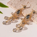 Detail of vintage gold tassel earrings with gray teardrop stones on beige stone background - 925 Silver Needle/Tassel Drop / Gold-Grey Glass Bead Tassel Style