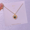 Gros plan d'un collier en or en forme de cœur avec pierre bleue sur carte de mode - Coeur Étoilé (XK001)