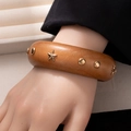 Detail van een bruine houten brede armband met gouden sterren en metalen klinknagels - Stijl L365-1 Ster en Ronde Studs