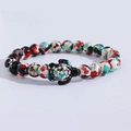 Detailed view of colorful speckled beads and a small sea turtle charm on the stretch bracelet - Red White Black Blue Green Splatter Turtle Bracelet