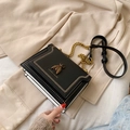 Black leather bee crossbody bag with gold chain and insect emblem on beige coat - Black