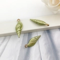 Detailed close-up of green shell-shaped metal charms with gold rings for DIY jewelry - Ocean Conch