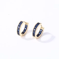 Detail view of gold huggie earrings featuring baguette-cut blue gemstones and bead edges - Gold Blue Zirconia