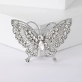 Macro shot of silver butterfly brooch with white rhinestones on geometric stone block - Silver