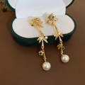 Detailed close-up of pearl drop earrings with gold bamboo motifs on a velvet jewelry box - 39# Bamboo Joint Pearl Ear Clip - Gold
