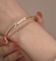 Close-up of elegant gold knot bracelet with sparkling cubic zirconia on a wrist - Knot Bangle / Gold