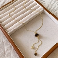 Elegante collana a Y dorata con perla occhio di tigre su vassoio in velluto beige - Collana Regolabile con Ciondolo a Forma di Piccola Sfera Dorata e Occhio di Tigre