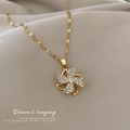 Dettaglio di una collana dorata con pendente a mulino a vento rotante e cristalli lucenti - Stile Girandola D'oro