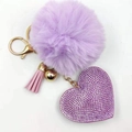 Close-up of purple faux fur pompom keychain with rhinestone heart and gold tassel - Violet