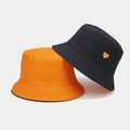 Détail du chapeau en coton montrant la broderie cœur et la texture du tissu canevas - Taille unique / Noir et Orange Réversible