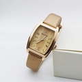 Detailed close-up of golden tonneau women's watch with crystal accents on a white stand - Gold