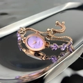 Detail of rose gold quartz watch with purple leaf stones on a reflective silver tray - Purple