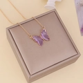 Detailaufnahme eines lila Schmetterlingsanhängers mit Goldkette auf einer Schmuckschatulle - Hellviolett