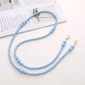 Detailed view of blue acrylic beaded crossbody chain with golden lobster clasps on magazine - Acrylic Beaded (K1283) / Blue