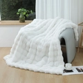 White faux fur blanket with 3D striped texture on a grey modern armchair in a cozy room - White