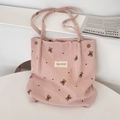 Dettaglio della borsa tote in velluto a coste rosa con ricamo di orsetto e etichetta - Rosa
