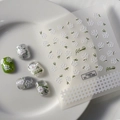 Macro detail of 5D embossed nail stickers featuring white floral patterns and green leaves - White Floral Style (FEB-285)