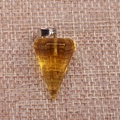 Close-up of a faceted amber crystal pendant with a metal clasp on woven fabric - Transparent Yellow