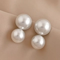 Detalle de elegantes pendientes de perlas redondas en dos tamaños sobre seda beige - Pin de Plata - Pendientes de Perlas Blancas