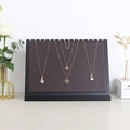 Black frame necklace display stand with brown wood texture holding three gold necklaces - Brown Leather