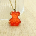 Close-up of orange resin bear pendant with gold star motifs on a thin gold chain - Big Red Lip Chain