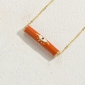 Golden necklace featuring a vibrant orange cylindrical evil eye enamel pendant - Brown