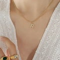 Gold plated titanium steel necklace featuring a sparkling letter R pendant on a female model - Letter R / Gold